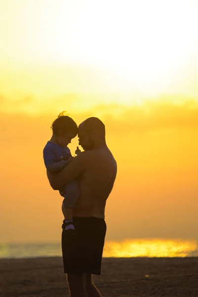 Silueta de bebé pequeño con padre al atardecer . — Foto de Stock