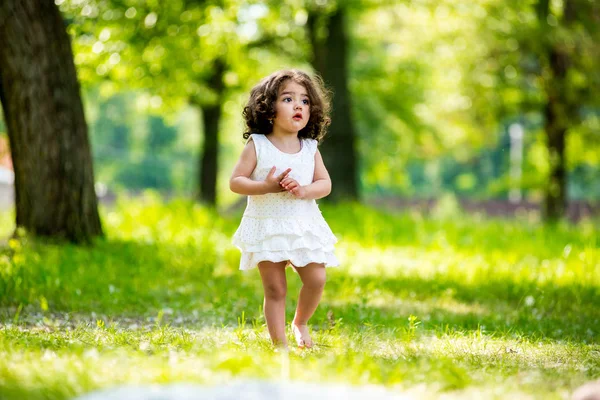 Pequena menina encaracolada andando no parque — Fotografia de Stock