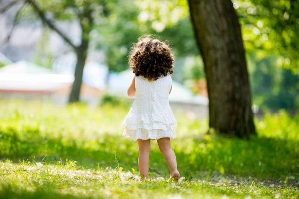 Pequeña chica rizada caminando en el parque —  Fotos de Stock