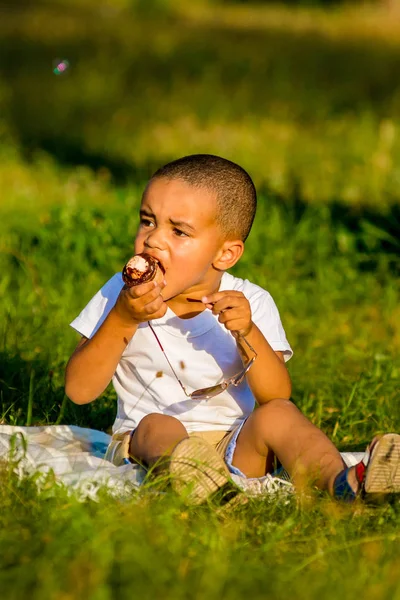 Adorable little black boy eating ice cream cone on the street — Stock Photo, Image