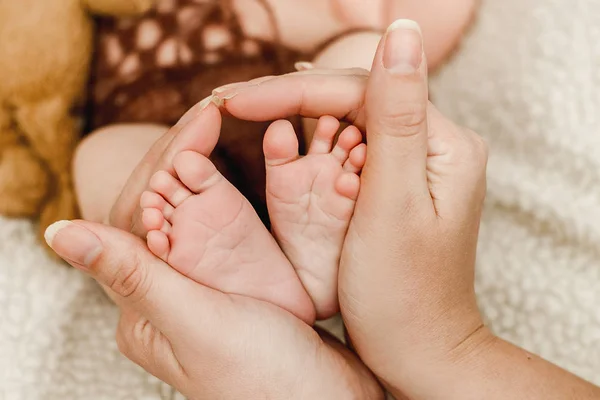 Os pés do recém-nascido nas mãos da mãe — Fotografia de Stock