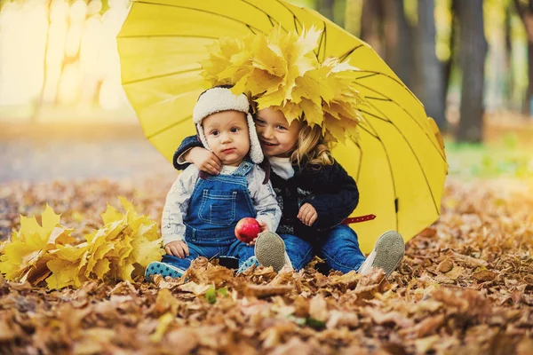 Niño pequeño con una niña bajo un paraguas de la lluvia otoño — Foto de Stock
