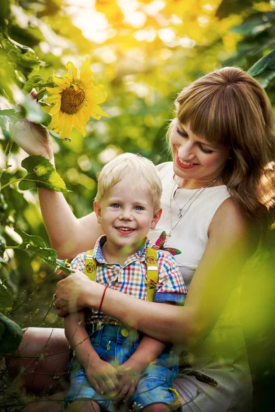 Молодая мама с маленьким сыном среди подсолнухов — стоковое фото