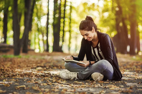 A menina com livro sentado debaixo da árvore — Fotografia de Stock