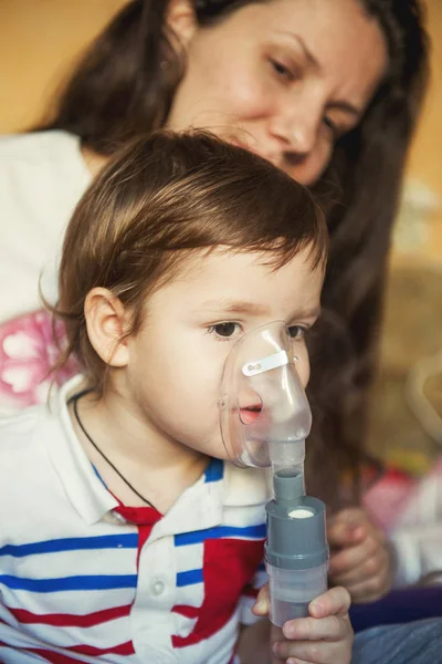 Jovem mulher com filho fazendo inalação com um nebulizador em casa — Fotografia de Stock