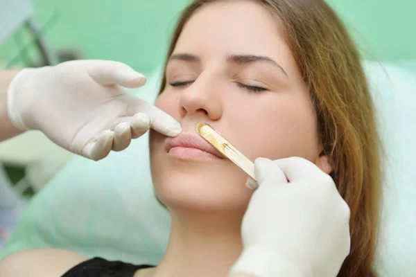 Removing the mustache of a woman with hot wax in a beauty salon