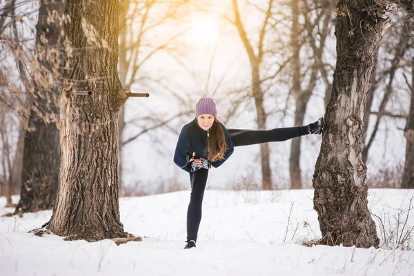 Sportowiec dziewczynka w zimie w parku robi ćwiczenia rozciągające — Zdjęcie stockowe