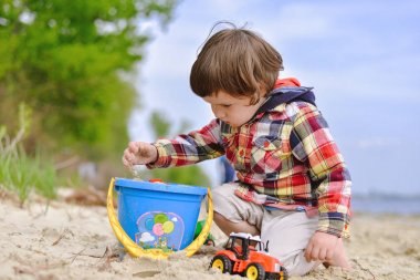 Sahilde çocuk kürek ve bir kova ile oynayan çocuk