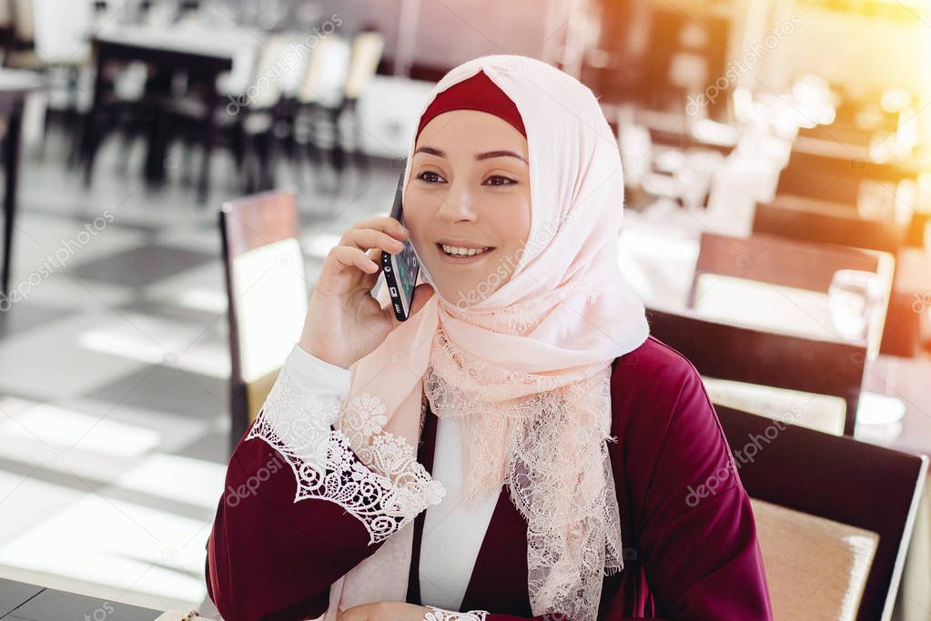 Muslim Woman Talking on Mobile Phone in a Cafe