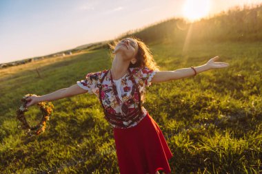  Doğa alanında kız. Kız çiçek çelenk ile neşeli iplik onun elinde olduğunu.