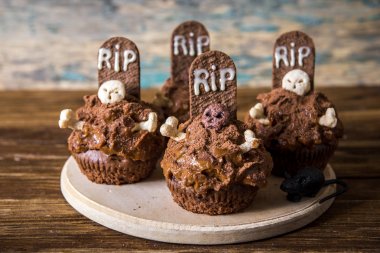 Mezar taşı pasta topper ve eski bir ahşap masa mum ile Halloween cupcakes