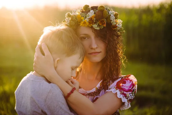 Een vrouw hugs zachtjes haar zoon op een groene weide op een Moederdag — Stockfoto