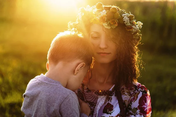 Een vrouw hugs zachtjes haar zoon op een groene weide op een Moederdag — Stockfoto