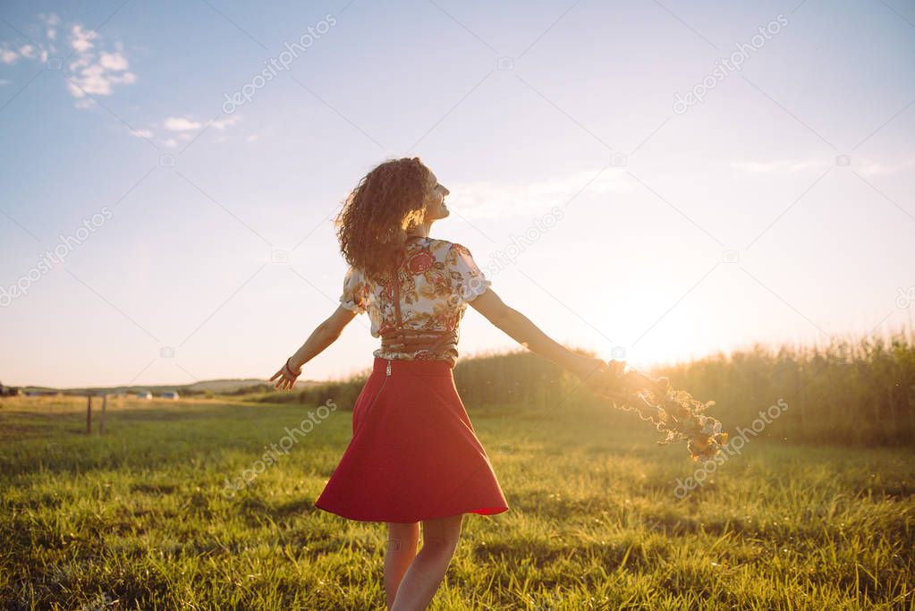 Girl enjoying nature on the field . The girl is joyful spinning with a wreath of flowers in her hands