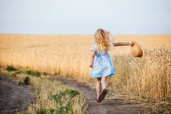 Gelukkig lopende meisje op een tarwe veld in het zonlicht — Stockfoto