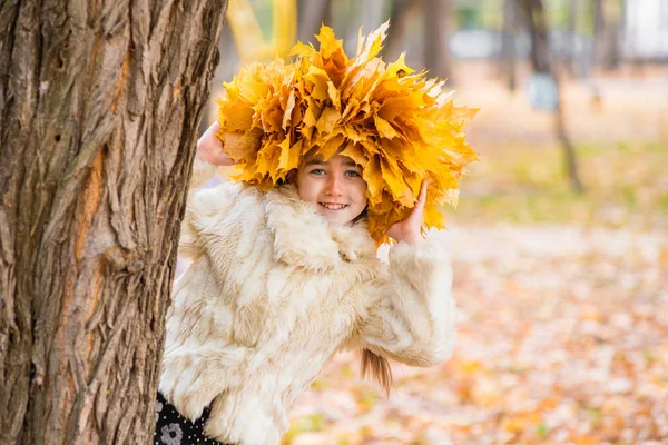 Linda menina em uma grinalda de folhas de bordo — Fotografia de Stock