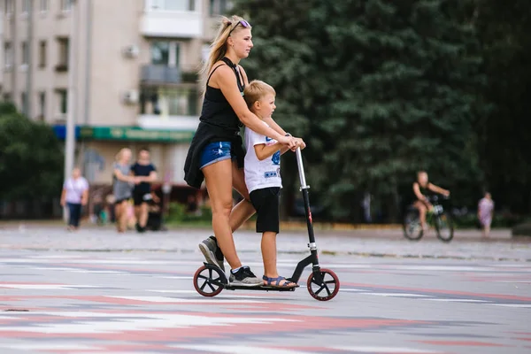 Mamá e hijo se divierten en unas vacaciones de primavera, montan en una moto y se divierten —  Fotos de Stock