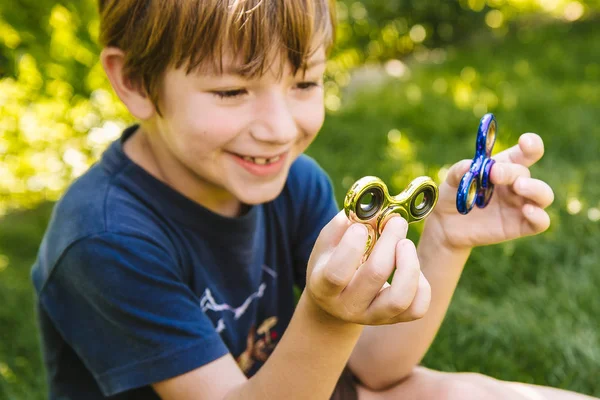 Çocuk iki topluca spinner ile oynarken stres giderici oyuncaklar açık