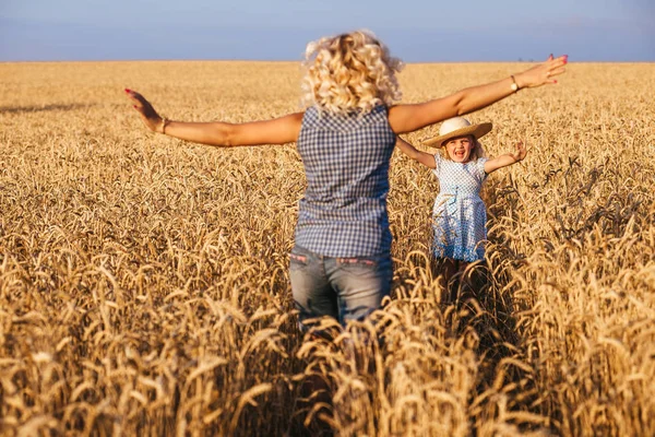 Mooie jonge moeder en haar dochter hebben plezier op het tarweveld — Stockfoto