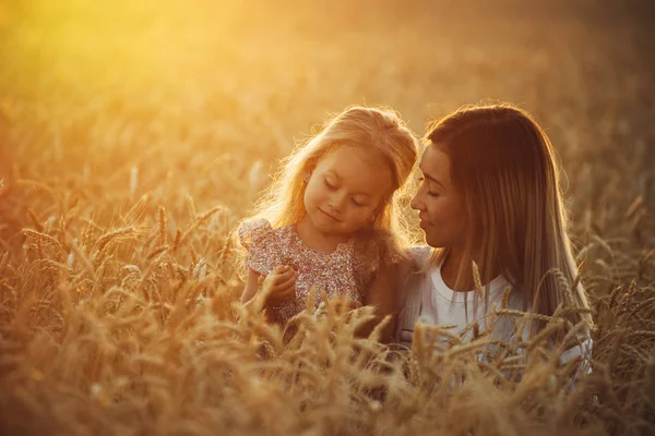 Mooie jonge moeder en haar dochter hebben plezier op het tarweveld — Stockfoto