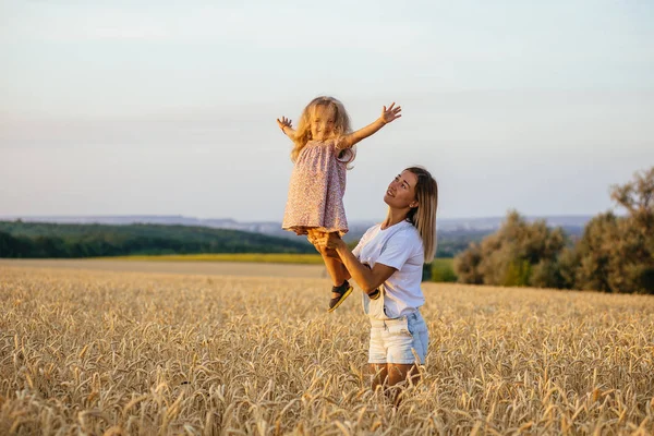 美しい若い母親と娘は小麦畑で楽しんでいます — ストック写真