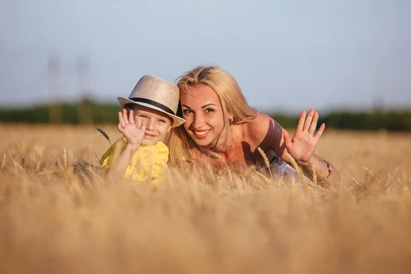 彼女の若い息子と麦畑の上を歩いて美しい若い母親. — ストック写真