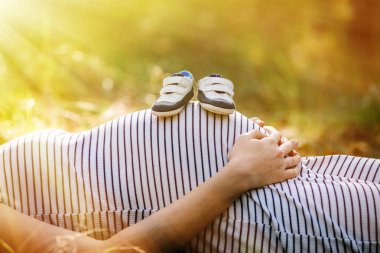 Hamile bir kadının karnı üzerinde patik Ayakkabı