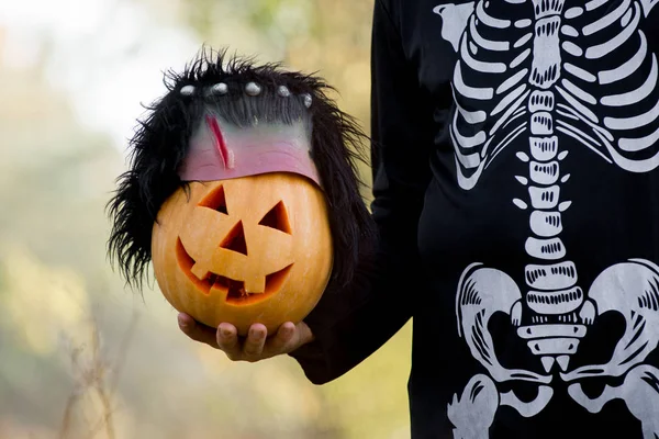 A man in a skeleton suit with a yellow pumpkin. Halloween Holiday — Stock Photo, Image