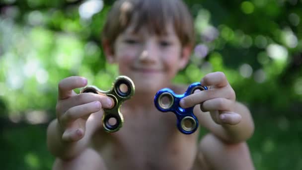 Pojke som leker med två fidget spinner stress lindra leksaker utomhus — Stockvideo