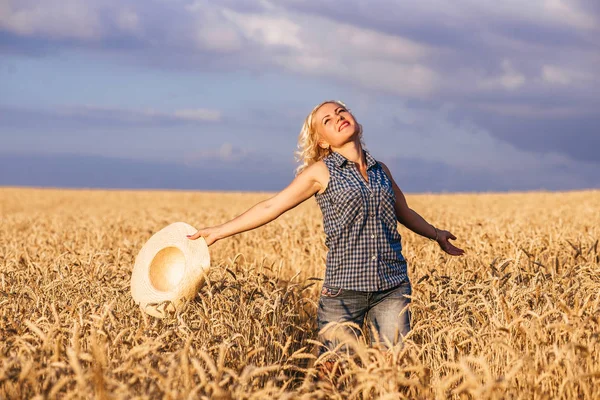 Güneşli bir günde, bir kadın bir doğa arka planda kavramı yaşam tarzı ekoloji çevre mutlu insanlar özgürlük, harika manzarasına hasır şapkalı beyaz bir elbise ile bir buğday alanı boyunca yürüyüş