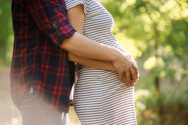 Adam hamile karısını göbek kucaklar. Mutlu ve genç hamile Çift.