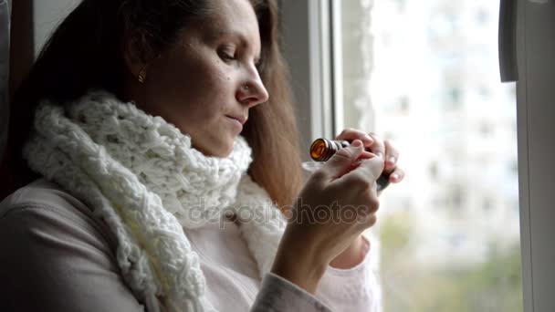 Sick woman sitting at the window of the house and drink the bitter medicine. Girl drinks a medicine. She is being treated for a cough. Treatment of influenza. — Stock Video