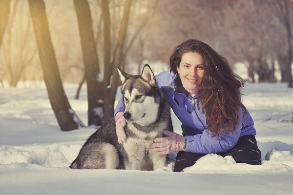Beautiful girl with Malamute in the park in winter — Stock Photo, Image