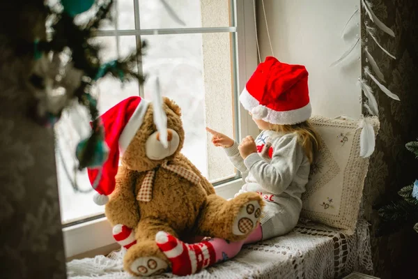Счастливая девочка, сидящая в зимнем окне Рождество Лицензионные Стоковые Изображения