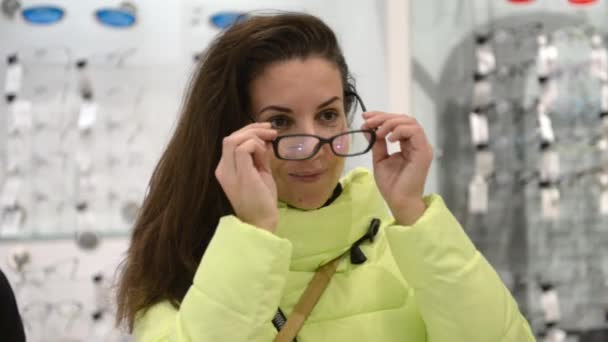 The girl is measuring the glasses in the store. The girl is engaged in shopping — Stock Video