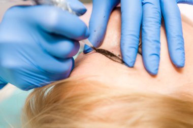 Ciltle bir güzellik içinde oturan düzgün, genç, güzel bir kadın. Bir güzellik kalıcı kaş kazançlar modelleme gerçekleştirir.