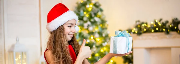 Gelukkig klein meisje glimlachend met geschenkdoos bij de kerstboom. Kerstconcept. — Stockfoto