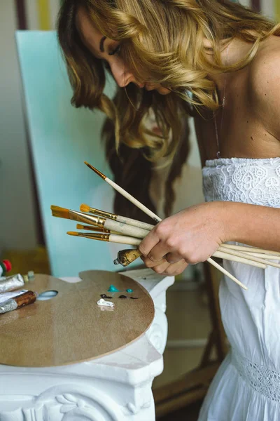 Artist paints picture on fabric with acrylic paints in her workshop