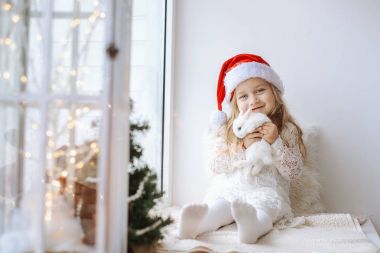 sevimli küçük kız Beyaz giysili Noel Baba şapkası beyaz küçük tavşan