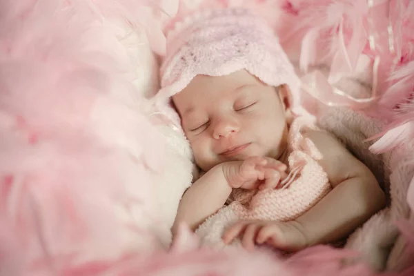 Bebé recién nacido durmiendo sobre un fondo de piel suave y cubierto de plumas rosadas con un enfoque suave para agregar elegancia . — Foto de Stock