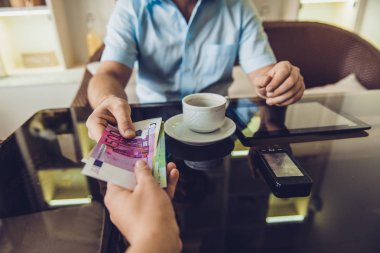 kafede oturan adam para başka bir adama veriyor.