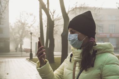 Kadın hasta ve giyen yüz maskesi acı. Kadın koruyucu maske şehrin hava kirliliği ile sokakta kötü hissediyor. Duman, çevre kirliliği.