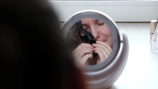 Uma Mulher Cuida Pele Rosto Usando Uma Máscara Preta Cosmética — Vídeo de Stock
