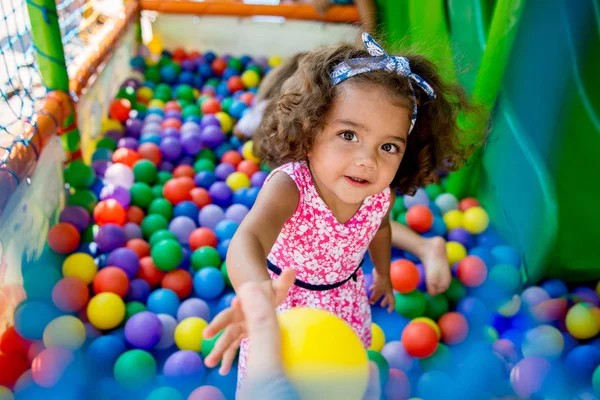 Menina feliz sentada em bolas coloridas — Fotografia de Stock