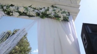 Arch düğün, çiçekler ve büyük Rüzgar kumaşlar ile dekore edilmiştir. Hareket halinde çekim. Düğün süslemeleri.