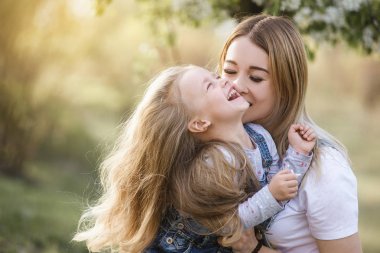 Genç anne ve güzel kızı parkta çiçek ağacıyla