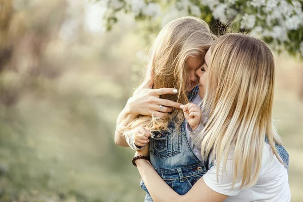 Giovane madre con adorabile figlia nel parco con albero di fiori — Foto Stock