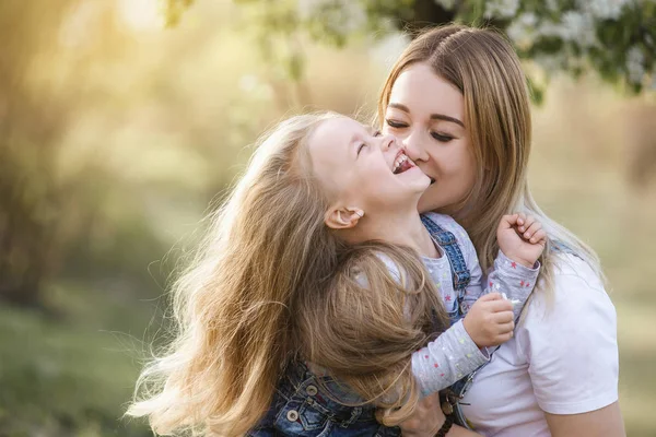Молода мати з чарівною дочкою в парку з розквітлим деревом — стокове фото