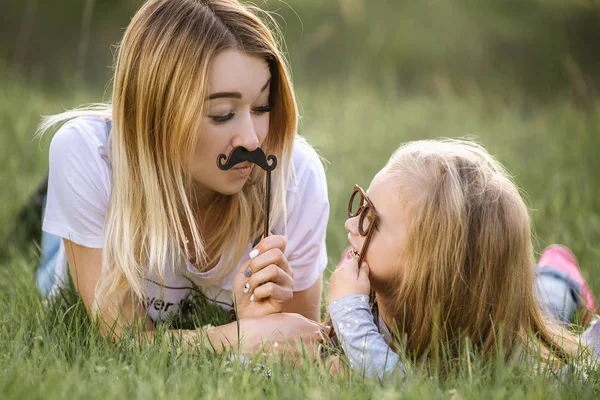 Divertida madre e hija posando con vasos de papel y bigotes —  Fotos de Stock