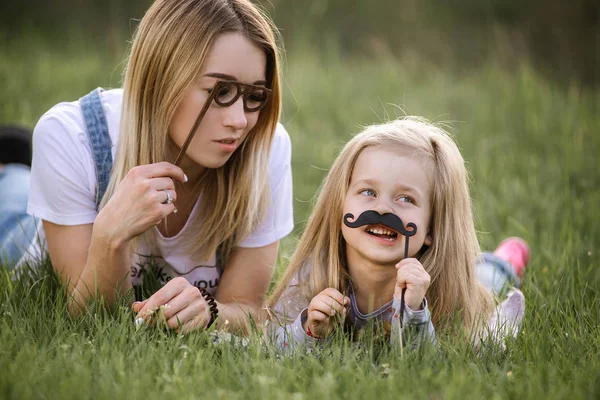Divertida madre e hija posando con vasos de papel y bigotes —  Fotos de Stock